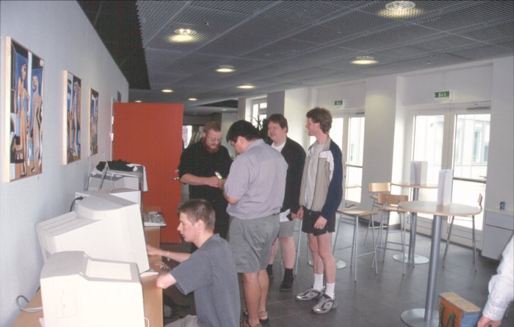 6: The lobby area outside the actual conference room. Gunne (GGSData) Steen's son, Emanuel, is setting up his OS4 68k/PPC system in the foreground, while Justin uses his new camera cell phone to snap a picture of Ole-Egil Hvitmyren and his AOne, and Pede and Thomas are watching.