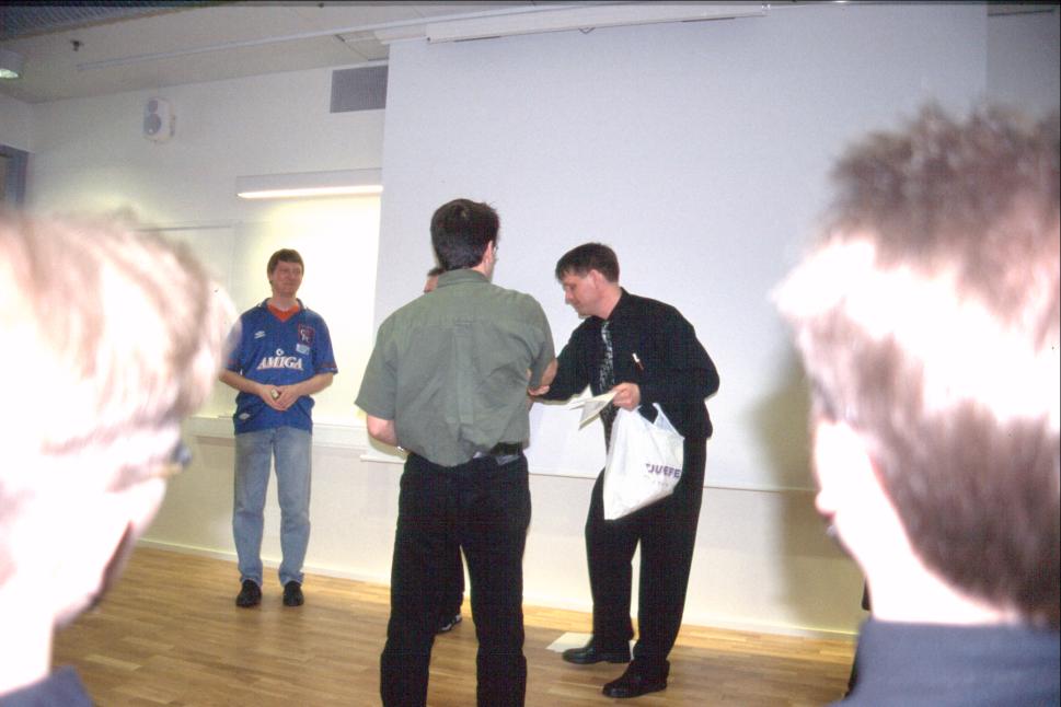 Tommy Strand from NAF handing out prizes for their own quiz, while Johan "Malmökillen" Wahlström in the blue Amiga shirt is getting ready to get his.